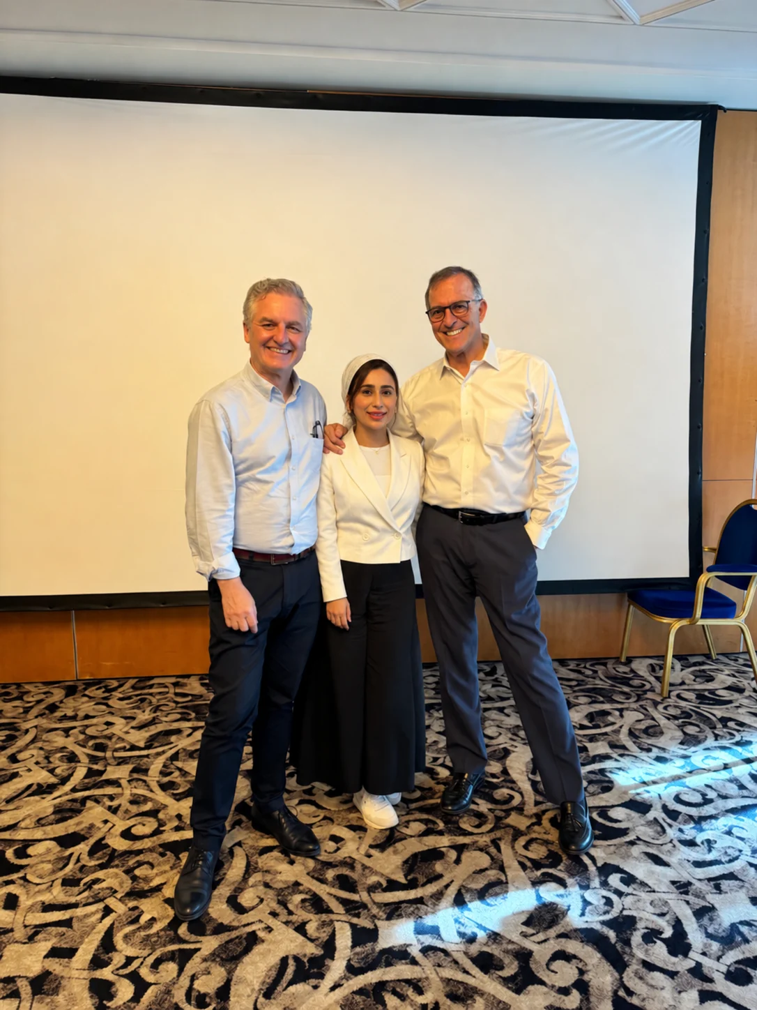Dr Amna Ali standing between Dr. Domingo Martin and Dr. Alberto Canabez at a conference in Bucharest, Romania