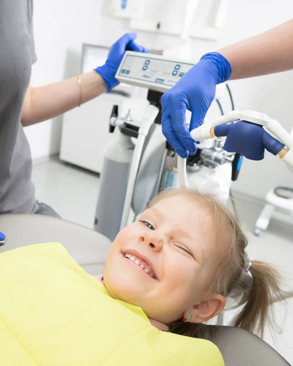 A young girl smiling in a dental chair during a check-up