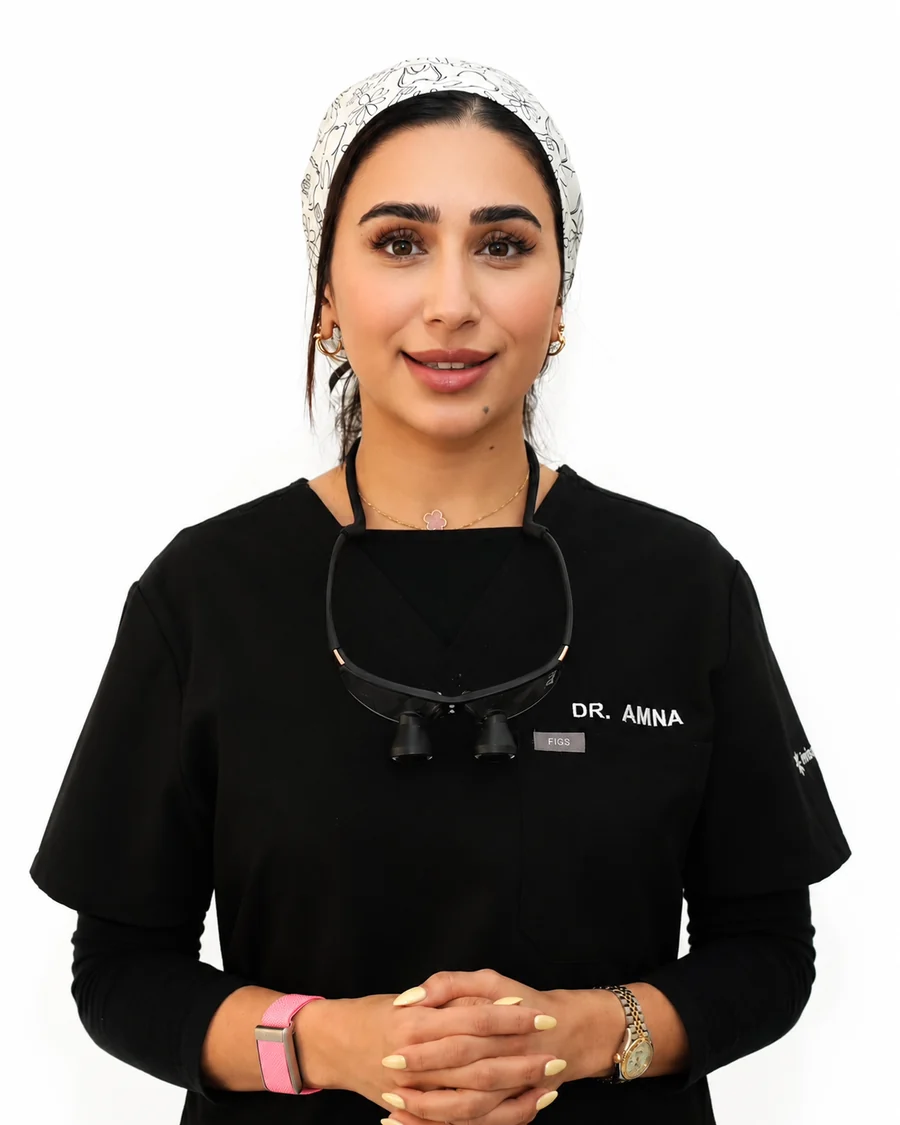 Portrait of Dr Amna Ali in clinic scrubs with loupes