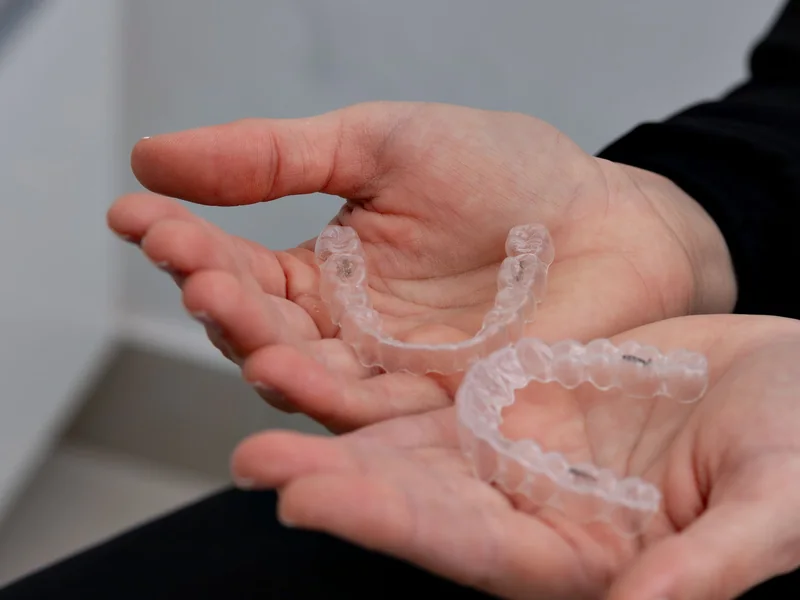 Clear removable retainer trays held in a clinician's hands